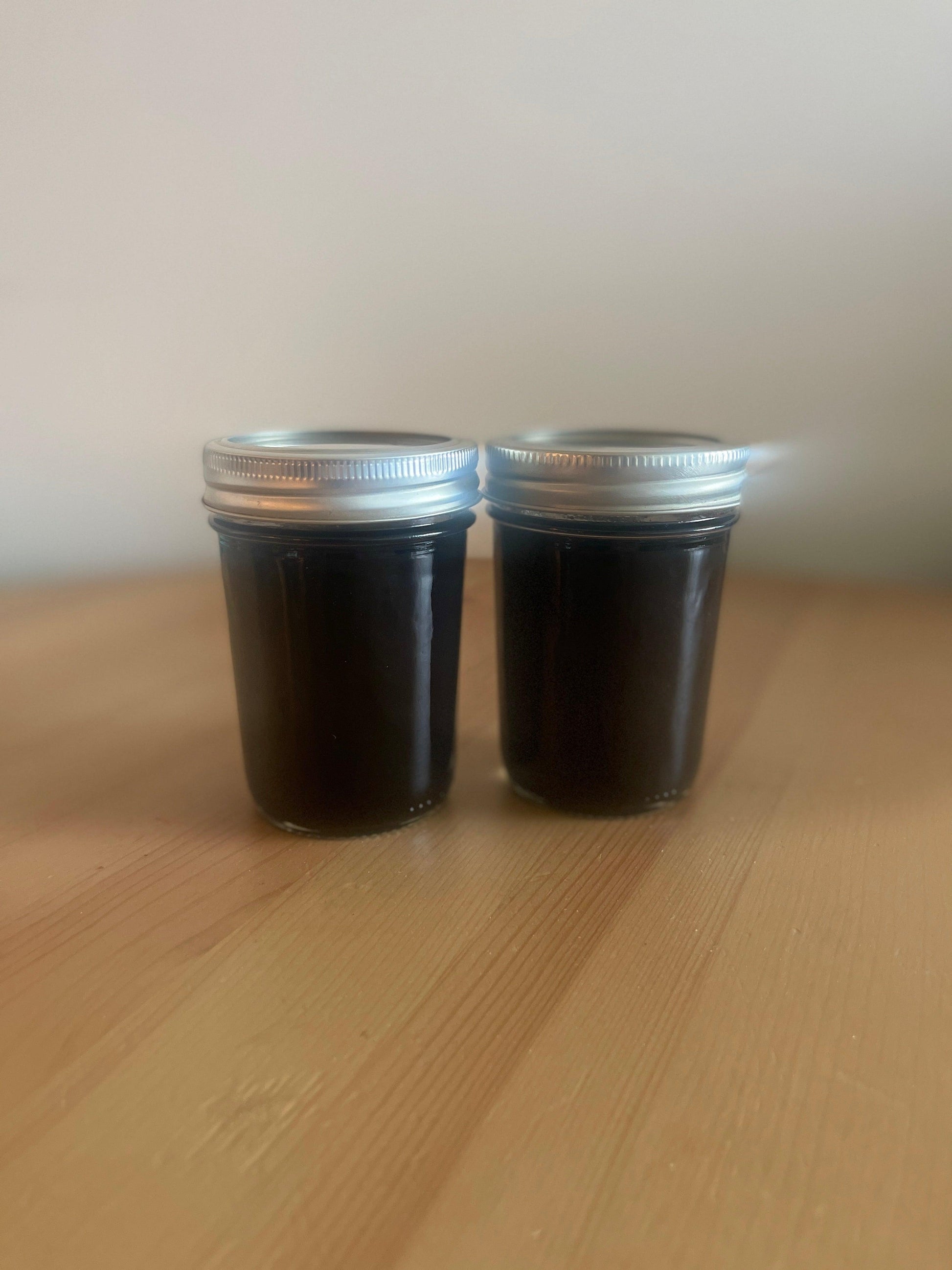 Photo of a bottle of all-natural Elderberry Syrup with organic agave nectar, a natural sweetener, available in 4oz, 8oz, and 16oz bottles, perfect for daily immune support during the change of season and allergy season